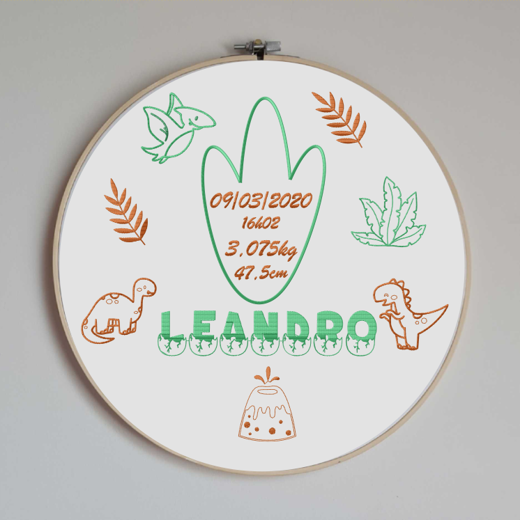 cercle en bois avec un tissu coton blanc brodé avec les informations de naissance de bébé (prénom, taille, poids, date et heure de naissance) avec des motifs sur le thème des dinosaures avec volcans, dinosaures mignons et plantes