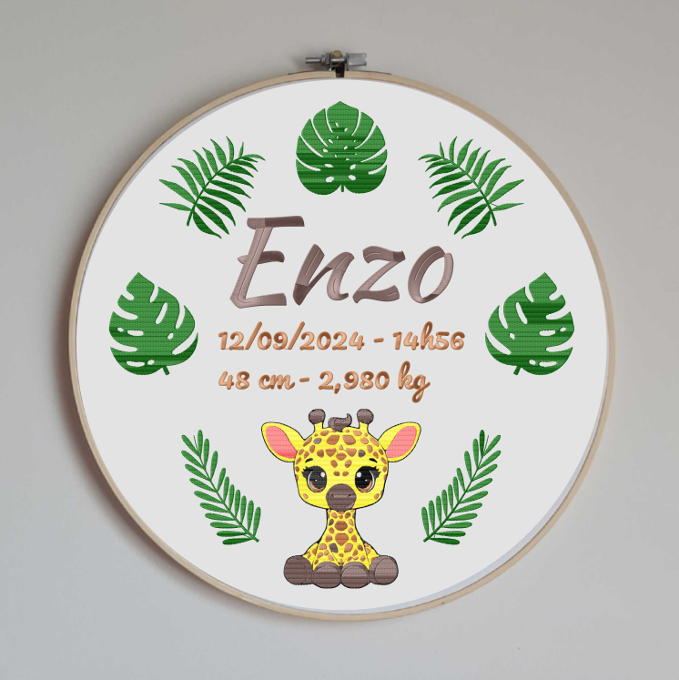 cercle en bois avec un tissu en coton blanc brodé avec les informations de naissance de bébé (prénom, taille, poids, date et heure de naissance) et des motifs sur le thème de la jungle avec un girafon