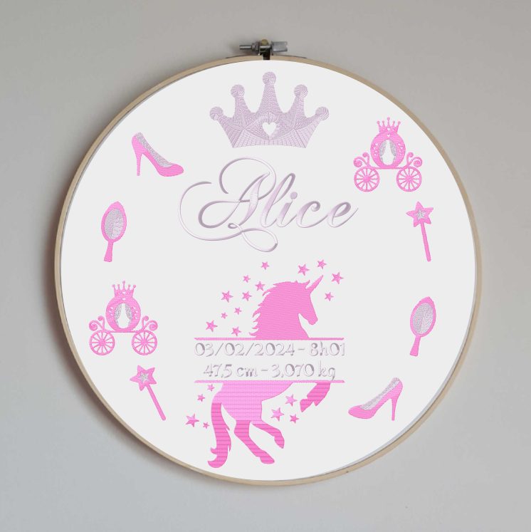 Cercle en bois avec un tissu coton blanc brodé avec toutes les informations de naissance de bébé et des motifs sur le thème des princesses et licornes