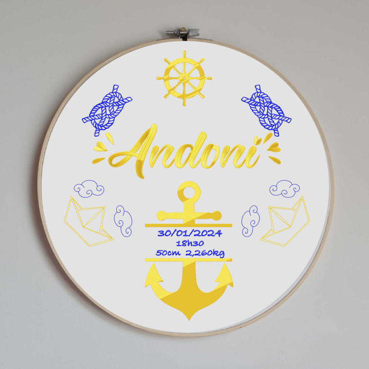 cercle en bois avec un tissu en coton blanc brodé avec toutes les informations de naissance du bébé et des motifs sur le thème marin avec une ancre